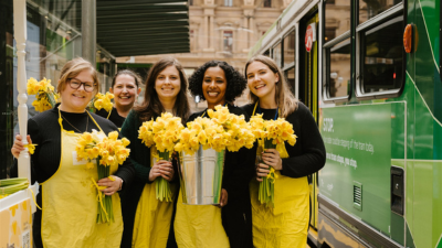 Cancer Council Victoria employees selling daffodils at one of the tram stops on Collins Street